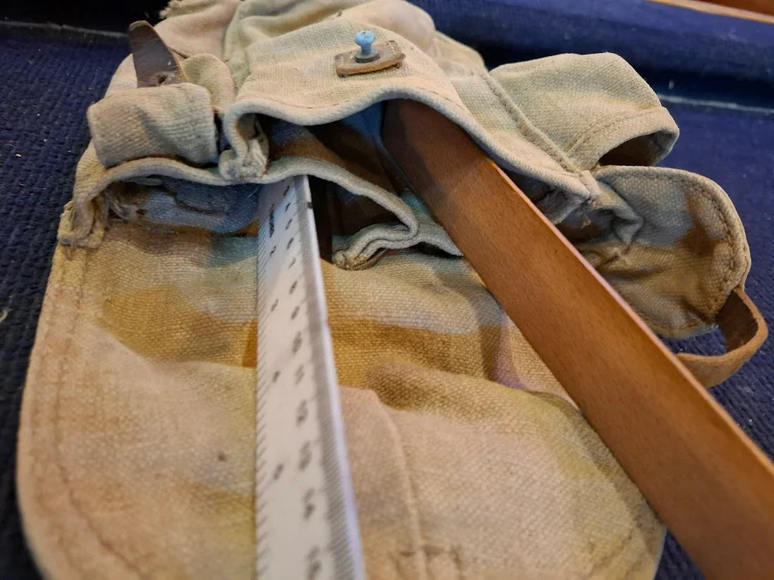 Vintage canvas tool pouch with wooden handle and measuring ruler on blue surface