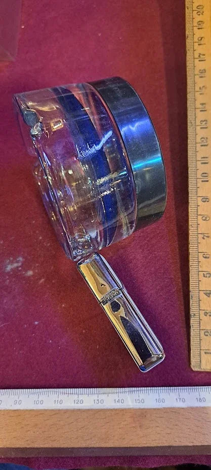 Vintage glass measuring jug with chrome handle on red surface, rulers for scale