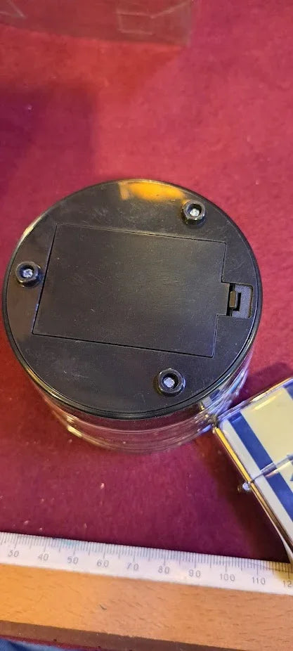 Battery compartment base of an antique collectible jar on a red felt surface, ruler nearby
