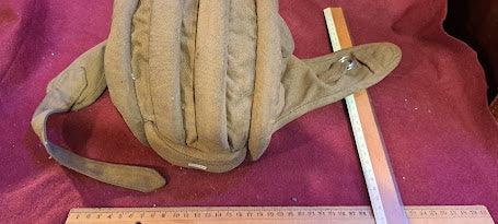 Vintage padded cap or helmet on maroon cloth, measured with rulers for size reference