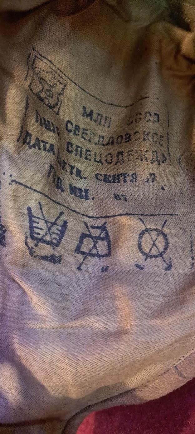 Vintage Soviet garment label with Russian text and care symbols on worn beige fabric