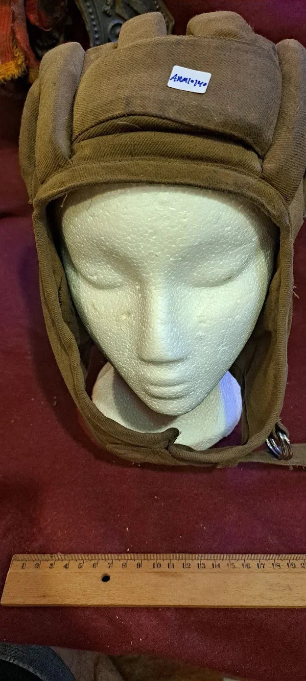 Vintage brown padded aviator cap on mannequin head with chin strap, ruler for scale