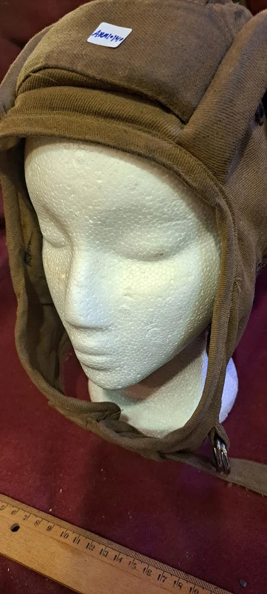 Vintage brown aviator cap on mannequin head, antique helmet with chin strap, ruler for scale