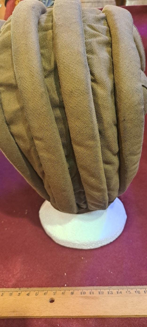 Antique padded brown turban on display stand with ruler for scale, collectible headwear