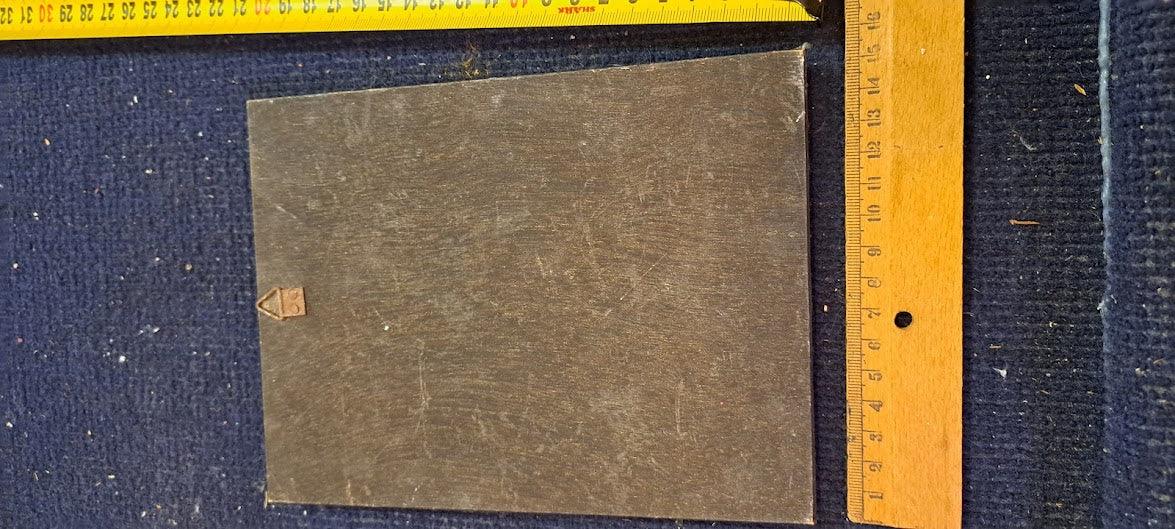 Vintage metal plate on blue fabric with measuring rulers for scale, collectible antique item