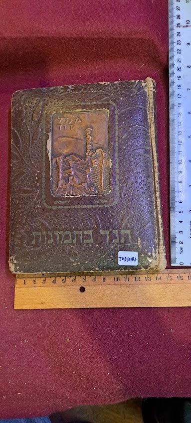 Vintage embossed Hebrew book with decorative cover, shown beside ruler for scale on red fabric.