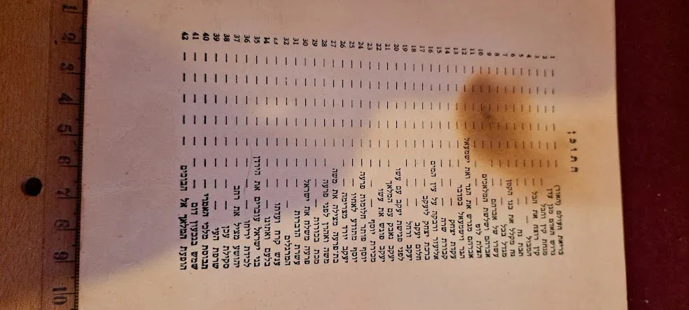 Vintage printed chart with typed text and a wooden ruler on a brown surface, collectible document.