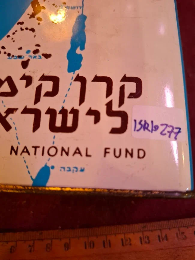 Vintage National Fund tin with Hebrew text, partial map, and a wooden ruler at the bottom.