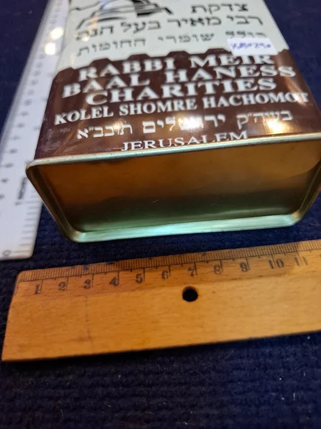 Vintage Rabbi Meir Baal Haness charity tin with Hebrew text, shown with rulers for scale
