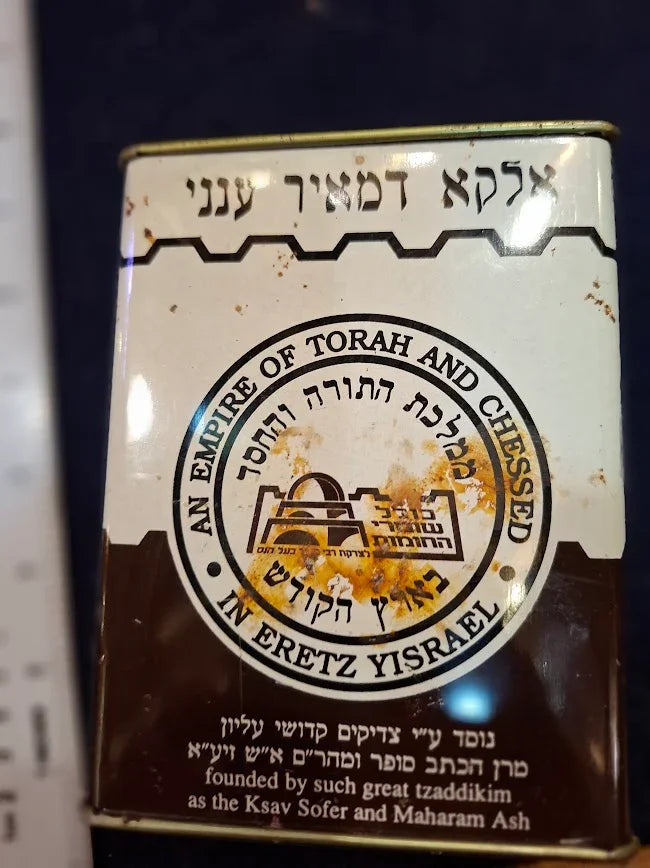 Vintage charity tin with Hebrew and English text, featuring an emblem and aged appearance.