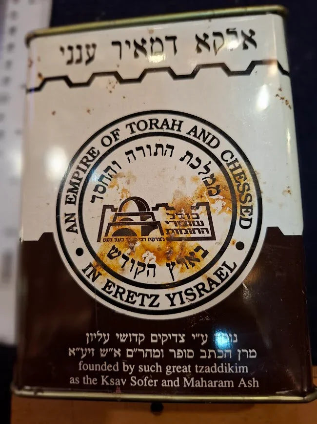 Vintage metal charity tin with Hebrew and English text, decorative seals, and rust marks
