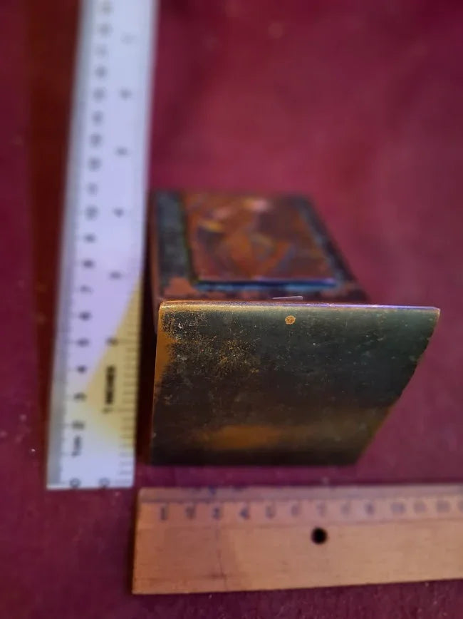 Vintage brass and wood decorative box with ruler for scale on red background