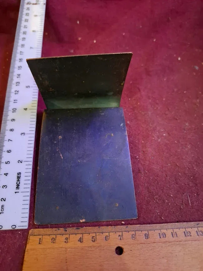 Vintage metal bookend on red surface, with rulers for scale, collectible antique item
